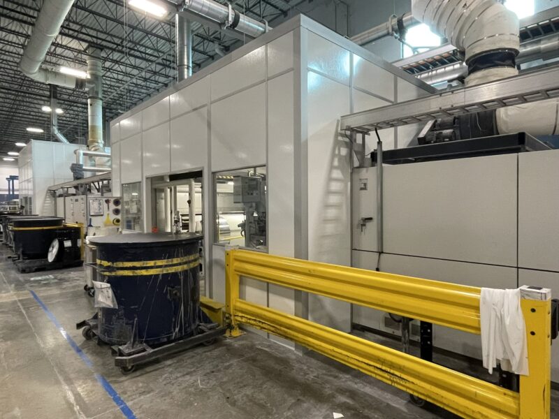 Industrial noise reduction enclosure for machines by MachineEnclosure.com installed on a production floor.