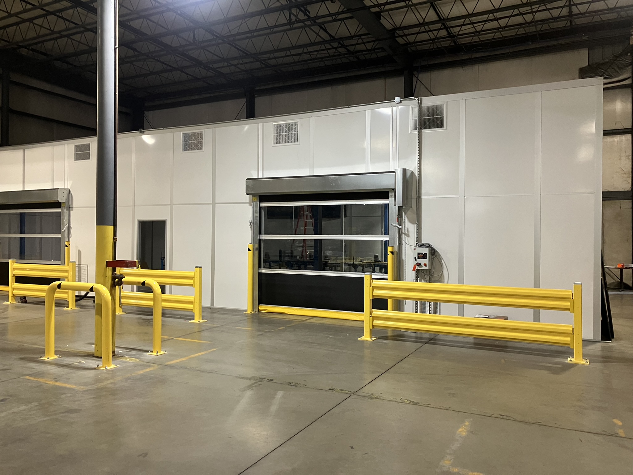 Machine safety enclosures with high-speed roll-up doors by MachineEnclosure.com in a warehouse setting.