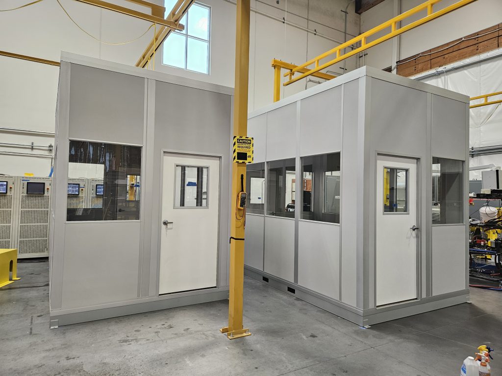 Freestanding modular equipment shelters by MachineEnclosure.com in a warehouse facility.