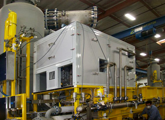 Custom equipment enclosure by MachineEnclosure.com installed over industrial machinery in a factory setting, featuring sealed panels and integrated piping.