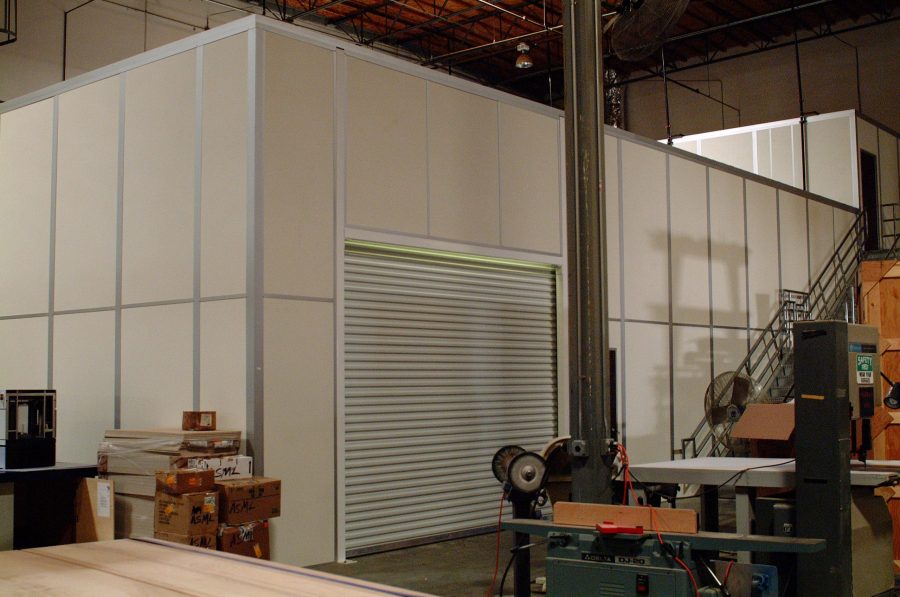 Modular machine safety enclosures with windows and doors by MachineEnclosure.com in an industrial facility.